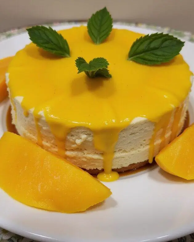 Finished Gateau à la Mangue Exotique garnished with fresh mango and mint, perfect for serving.