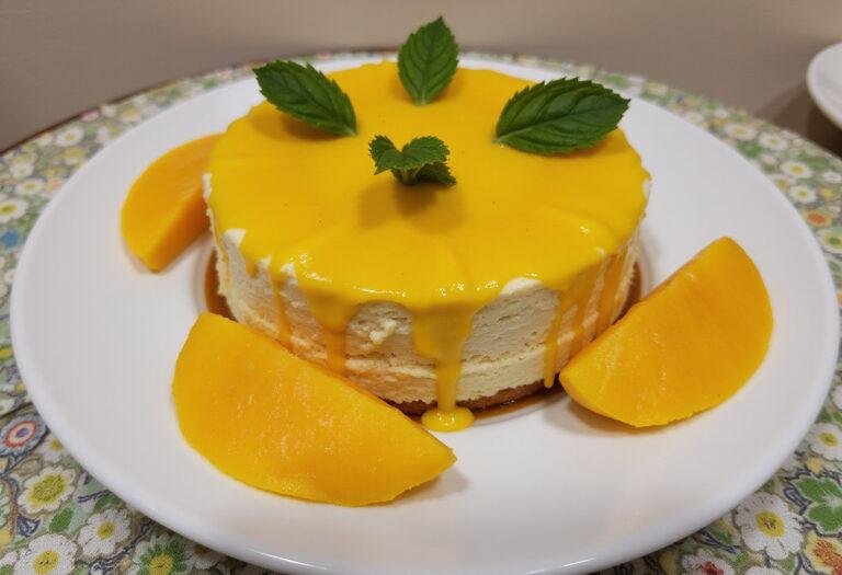 Finished Gateau Ă la Mangue Exotique garnished with fresh mango and mint, perfect for serving.