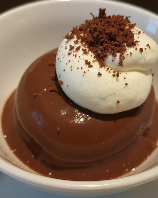 Déguster une mousse au chocolat 2 ingrédients présentée avec de la crème fouettée et des copeaux de chocolat.