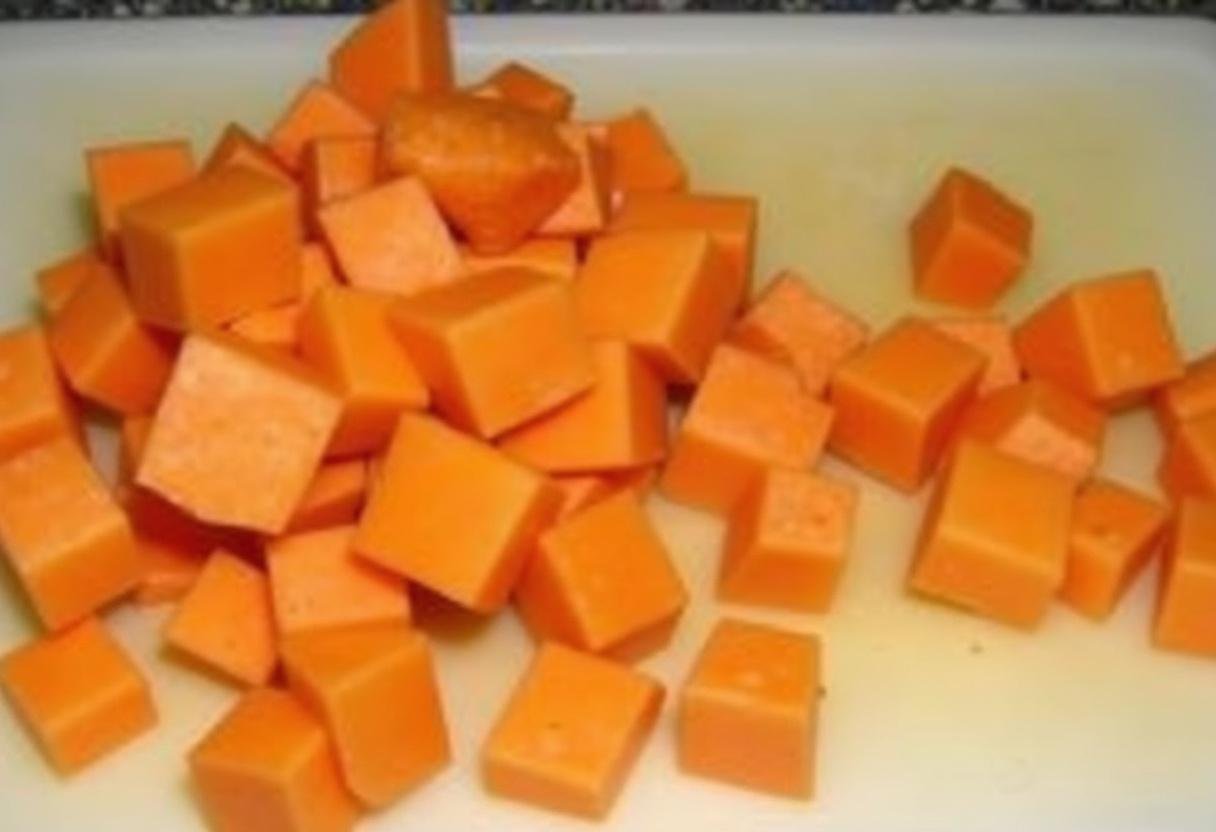 Préparation de patates douces pelées et coupées en cubes pour la recette de patate douce au four rapide.