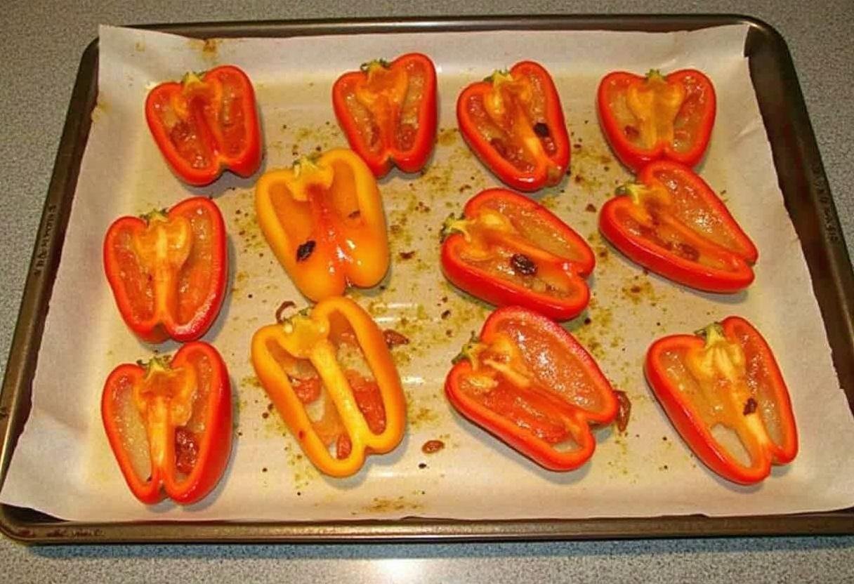 Une plaque de cuisson chaude avec du papier sulfurisé dans le four, prête à griller des poivrons au four marinés.