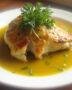 Poulet onctueux à la sauce moutarde servi dans une assiette blanche, délicatement garni d'herbes fraîches.