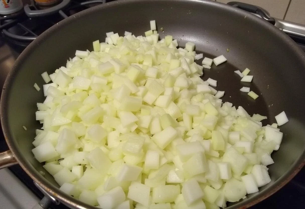 Skillet avec de l'huile d'olive, oignons en dés en train d'être sautés pour le riz aux crevettes.